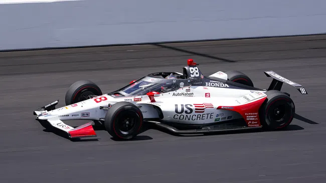IndyCar race car number 98 with US Concrete livery racing on track at high speed under clear skies