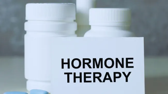 White medication bottles with blue pills scattered and a card reading hormone therapy in focus