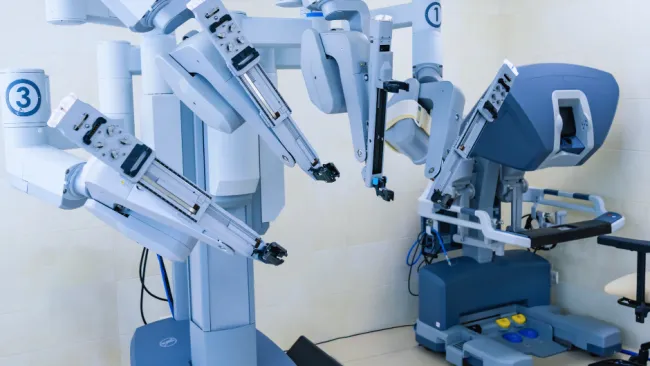 Robotic surgical system with multiple articulated arms and surgeon console in a medical operating room.