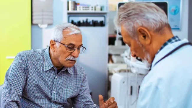 Senior man discussing medical documents with doctor in a clinical setting during consultation.