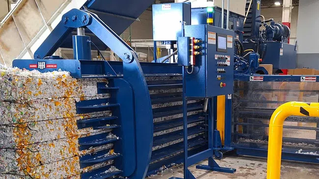 Industrial machine compressing and baling recycled paper in a warehouse environment