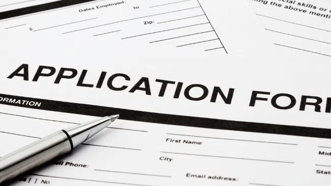 Close-up of blank application forms with a silver pen ready for filling out personal and employment information.