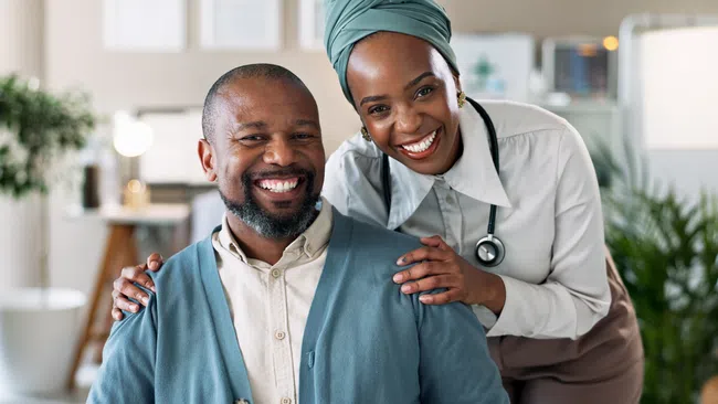 Smiling doctor with stethoscope embraces happy male patient in bright modern medical office setting