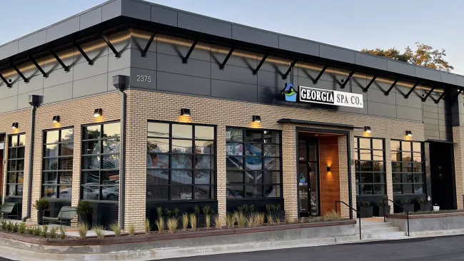 Modern Georgia Spa Co. building with large windows, brick facade, and exterior lighting at dusk