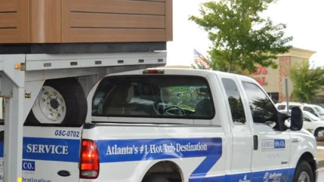 A service truck transporting a hot tub, promoting local hot tub destination services in Atlanta.