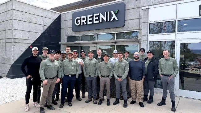 Group of Greenix employees standing outside the company's modern concrete office building under the Greenix sign.