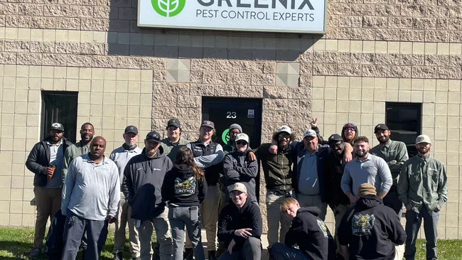 Group photo of Greenix Pest Control experts standing outside the company building under the Greenix sign