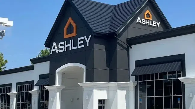 Exterior view of newly renovated Ashley furniture store with black and white facade under blue sky