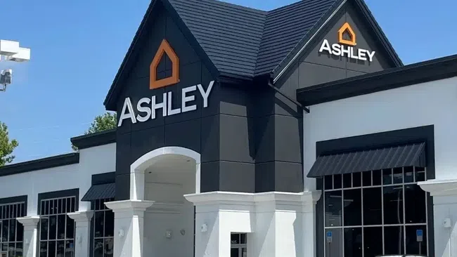 Exterior view of newly renovated Ashley furniture store with black and white facade under blue sky