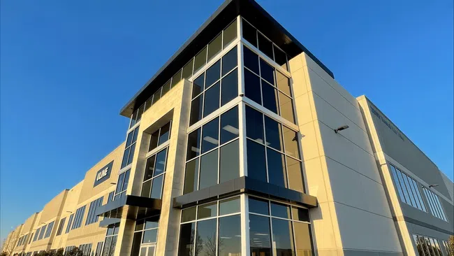 Modern commercial building with large glass windows under a clear blue sky during sunset.