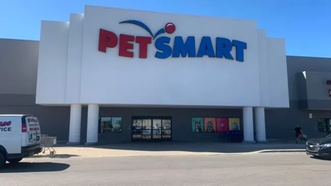 PetSmart storefront with large red and blue logo on white facade under clear blue sky.