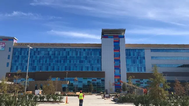 Exterior view of Our Lady of the Lake Children's Hospital with blue glass windows under a clear sky.