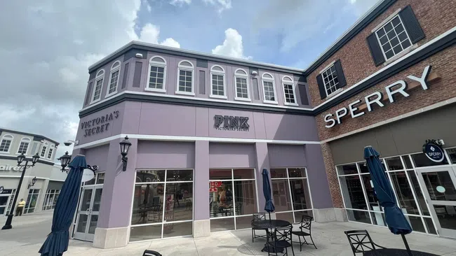 Outdoor seating area in front of Victoria's Secret and Sperry stores under a cloudy sky in a shopping center