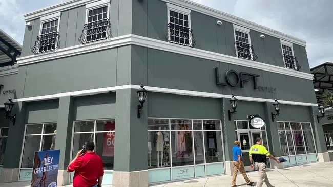 Two-story gray LOFT Outlet store with large windows and people walking outside on a sunny day.
