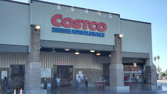 Costco Wholesale store entrance with visible signage and customers walking in and out during daytime.