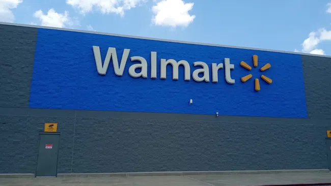 Exterior of a Walmart store with large blue signage and gray walls under a partly cloudy sky.