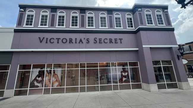 Victoria's Secret storefront with purple facade and large window displays featuring lingerie models under a cloudy sky