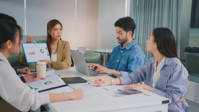 Business team discussing charts and data during a meeting in a modern office space.