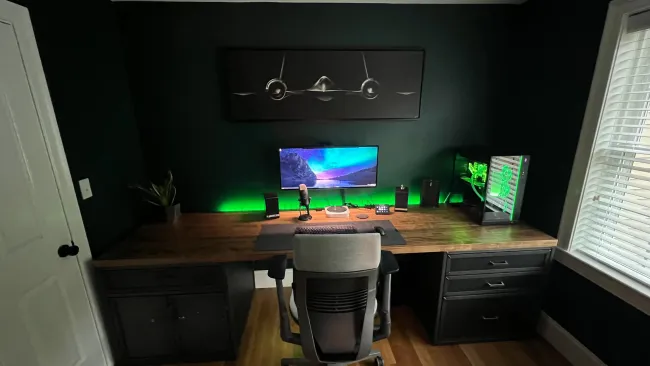 Sleek gaming and streaming setup with single monitor, RGB-lit PC, microphone, and ergonomic chair in dark room.