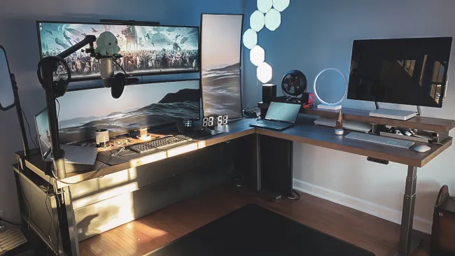 Modern dual monitor gaming and productivity desk setup with microphone, keyboard, laptop, and ambient lighting.