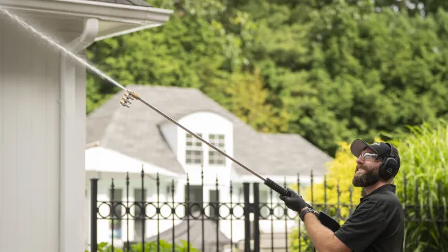 a man pressure washing a side of a house