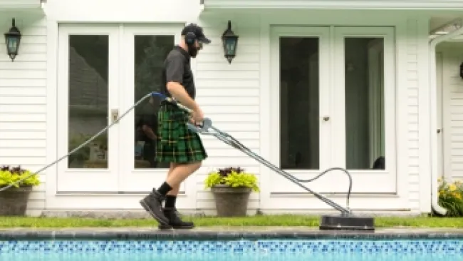 a man wearing a kilt and standing beside a pool