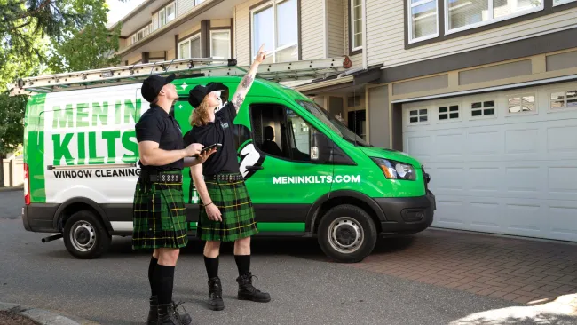 two people in kilts standing in front of a green van