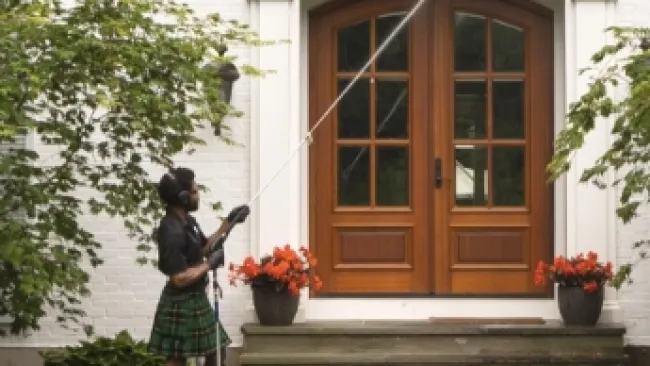 a person in a kilt holding a cane in front of a house