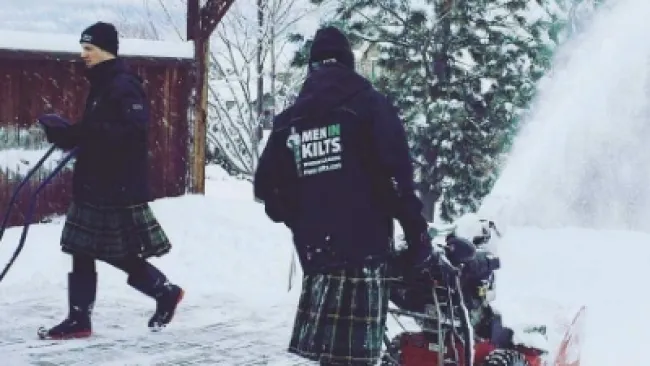 a couple of people on snow skis pulling a snowmobile