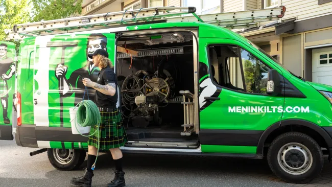 a person in a kilt standing next to a green van