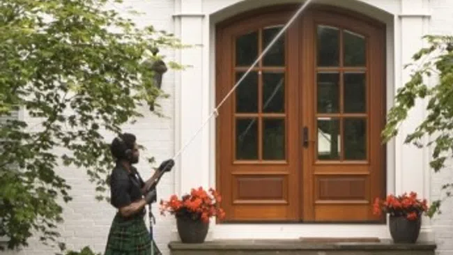 a person in a kilt holding a cane in front of a house