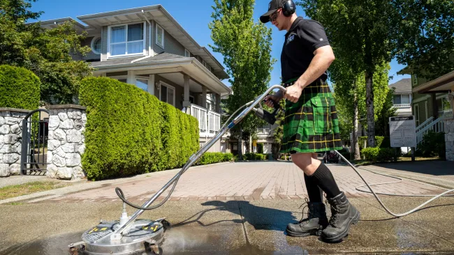 a man washing the sidewalk in front of houses