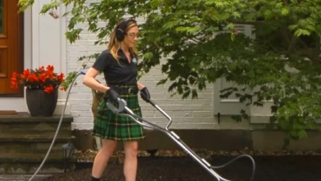 a woman using a surface washer on a sidewalk