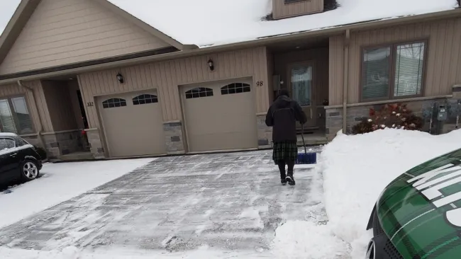 a person shoveling snow in front of a building