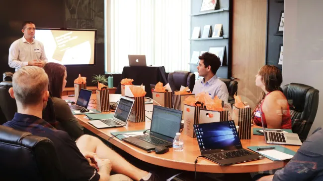 A team meeting in a conference room with laptops and presentation materials.