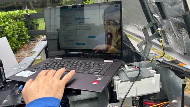 Technician using laptop to test and repair electrical components inside a home standby generator..