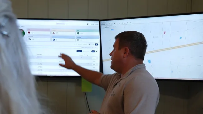 Man in polo shirt explaining data on dual screens showing florida pan handle sites of installation and repair of home standby generator brands such as Generac, Briggs and Stratton, and Kohler power systems