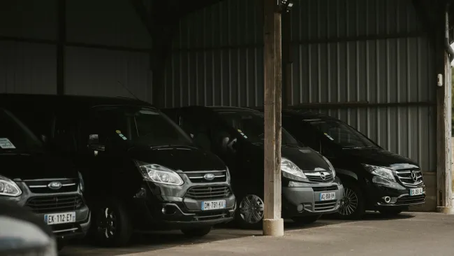 Red semi-truck driving on a highway with cars and leafless trees under cloudy sky.