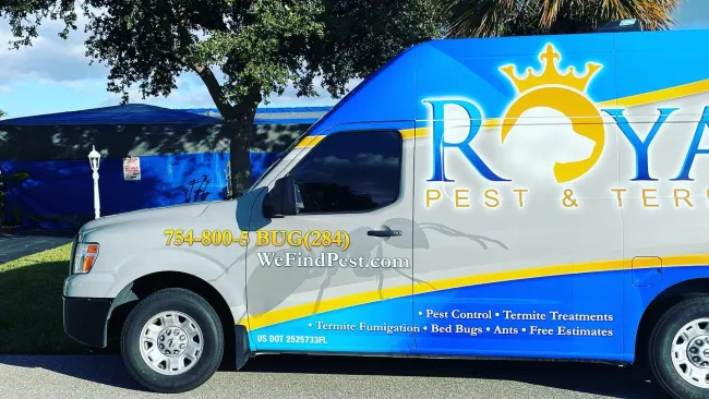Royal Pest & Termite service van parked outdoors with phone number and service details on side.
