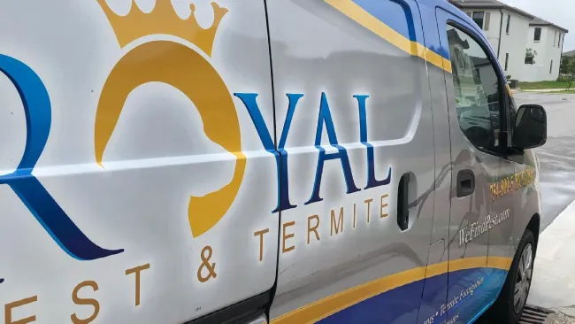 Side view of Royal Pest & Termite service van with company logo and contact information on a residential street.