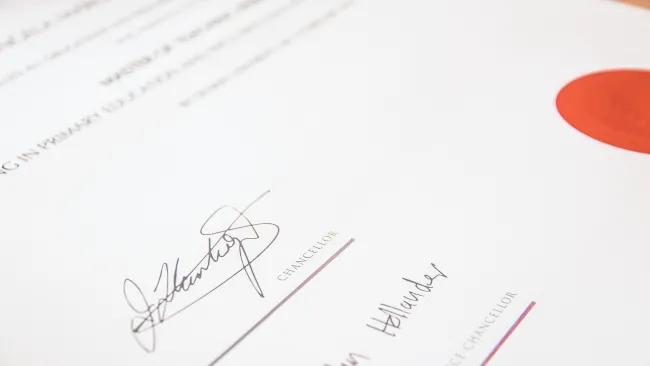 Close-up of a signed official document with signatures and a red seal stamp on white paper.