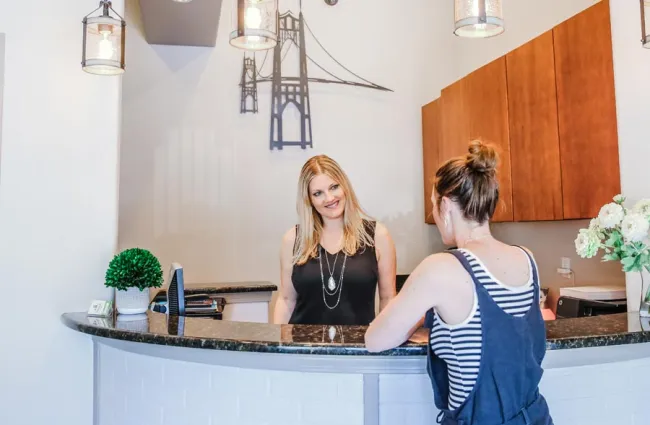 a woman standing next to a woman sitting at a counter