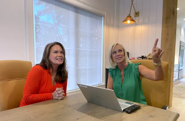 a couple of women sitting at a table with a laptop