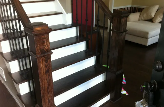 Dark wood staircase with white risers and black iron balusters in a modern home interior.