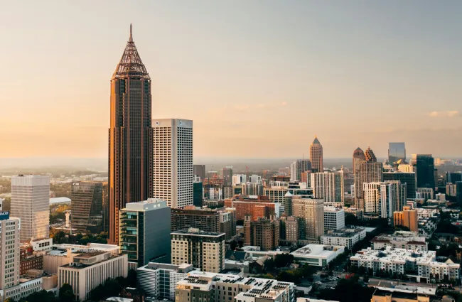 Aerial view of Atlanta city skyline at sunset with tall buildings and warm glowing sky.