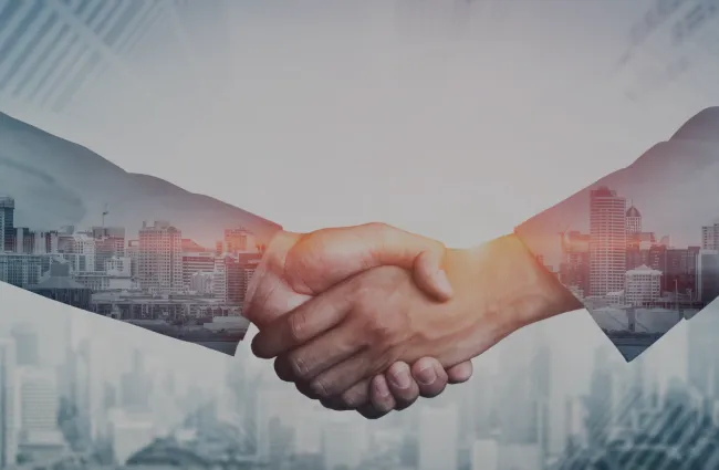 Two hands shaking with a cityscape in the background, symbolizing partnership and collaboration.