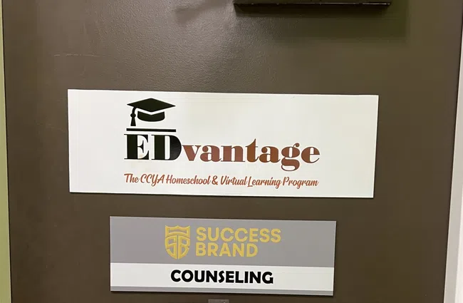 Brown door with signs for EDvantage homeschool program, Success Brand counseling, and a note to keep door closed.