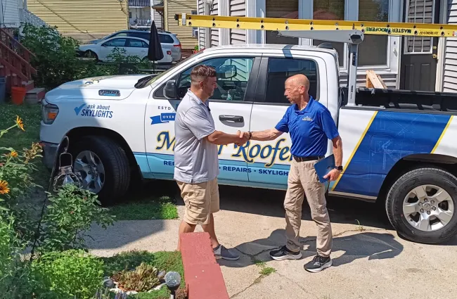 a couple of men standing next to a white truck