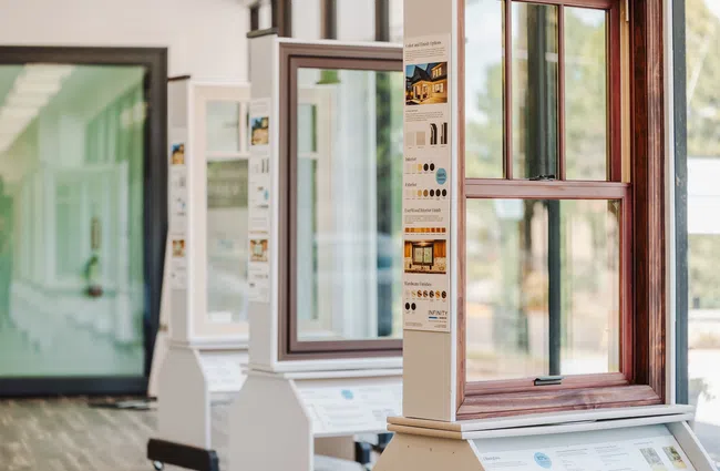 Display of various residential window designs in a showroom highlighting styles and finishes.