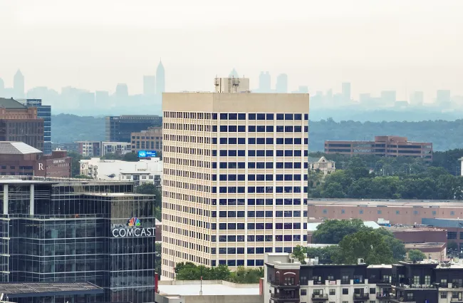 Cityscape featuring Comcast building amid urban office and residential towers with distant skyscrapers on a hazy day